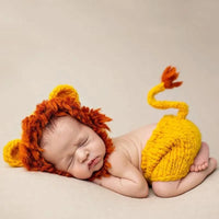Thumbnail for Newborn baby wearing a lion costume with a red mane and yellow body on a beige background