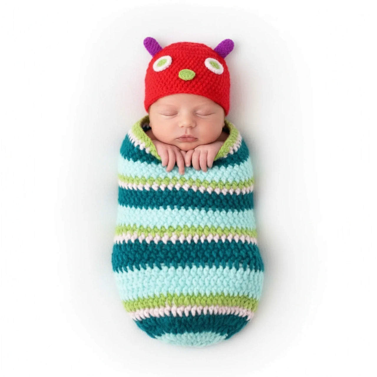 Newborn baby wrapped in a striped swaddle with a colorful hat on a white background