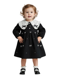 Thumbnail for Child wearing a black dress with white collar and bow details on a white background