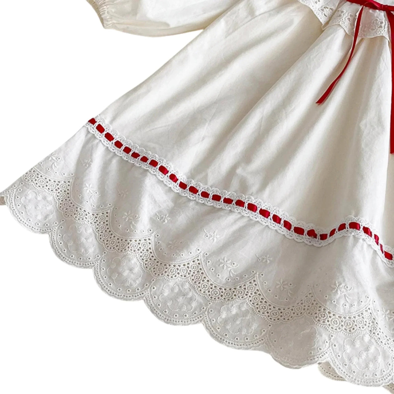 Close-up of a white dress with red trim on a white background