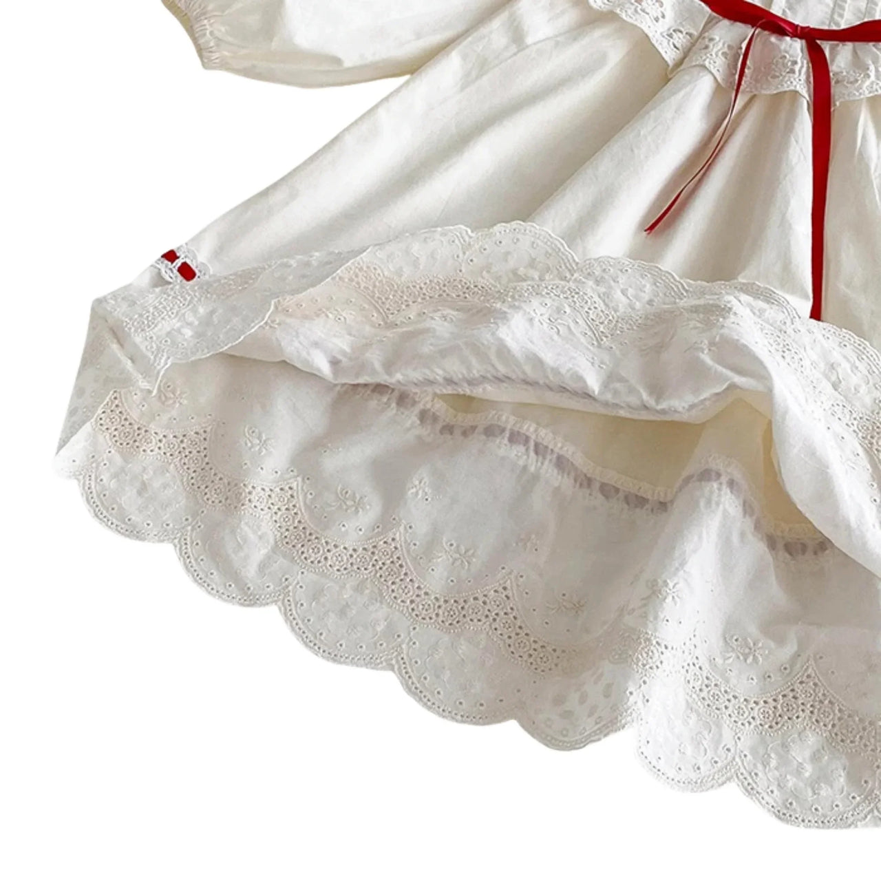 Close-up of a white dress with lace details and a red ribbon on a white background