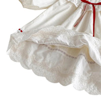 Thumbnail for Close-up of a white dress with lace details and a red ribbon on a white background