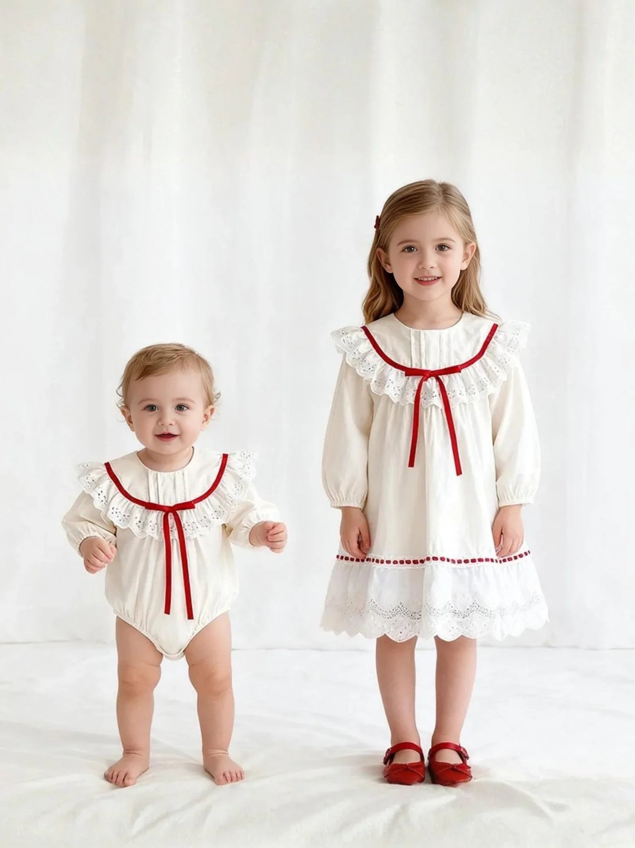 Two children wearing matching white outfits with red trim on a white background