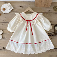 Thumbnail for White dress with red trim on a wooden surface