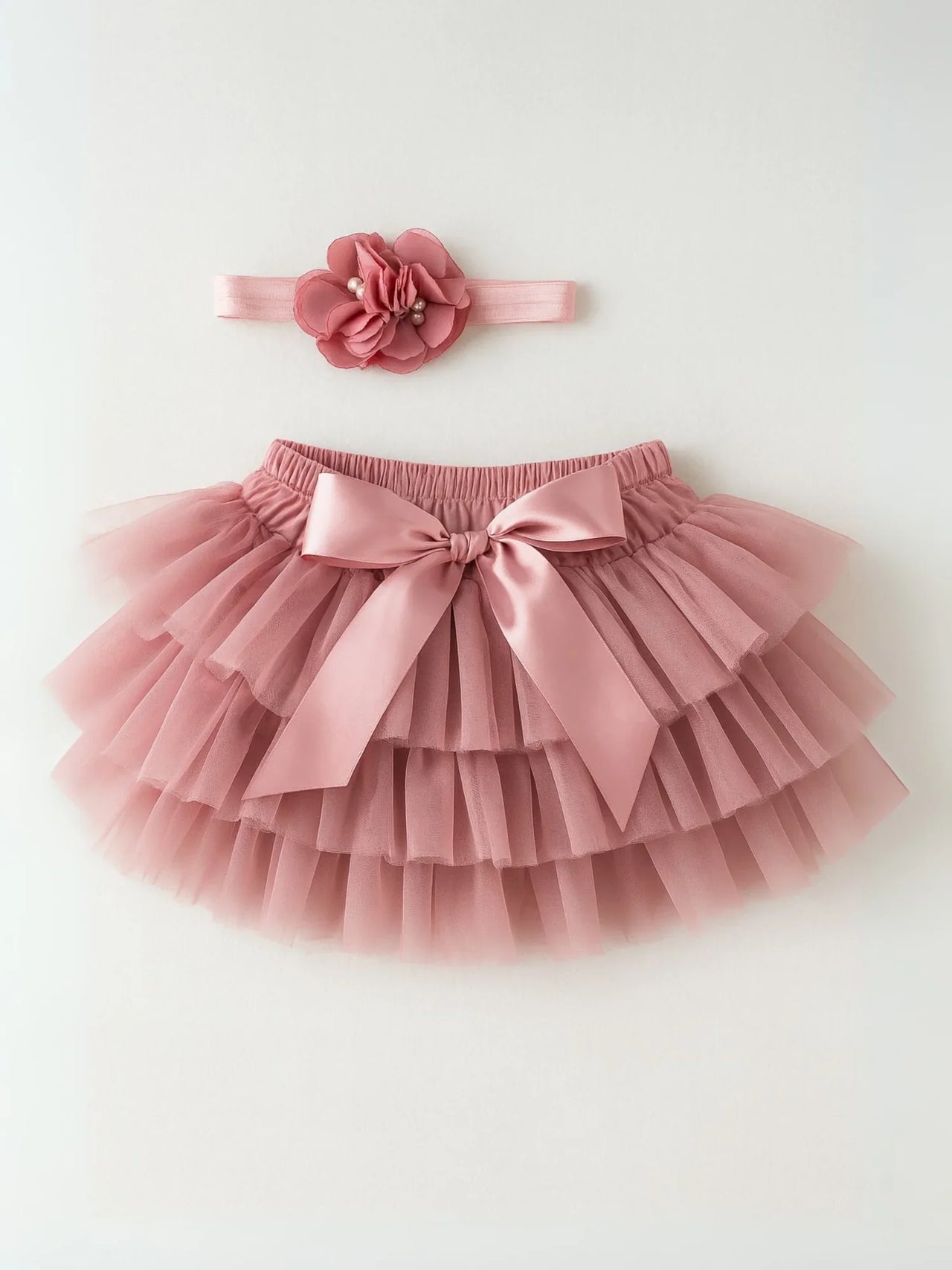 Pink tutu skirt with a bow and matching headband on a white background
