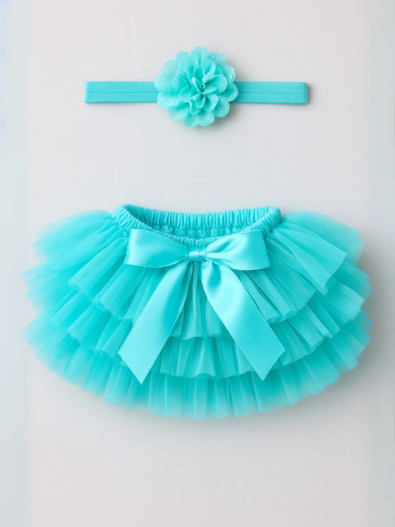Turquoise tutu skirt with matching headband on a light gray background