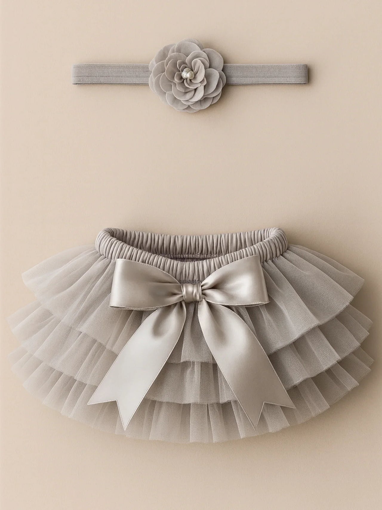 Gray tutu skirt with bow and matching headband on a beige background