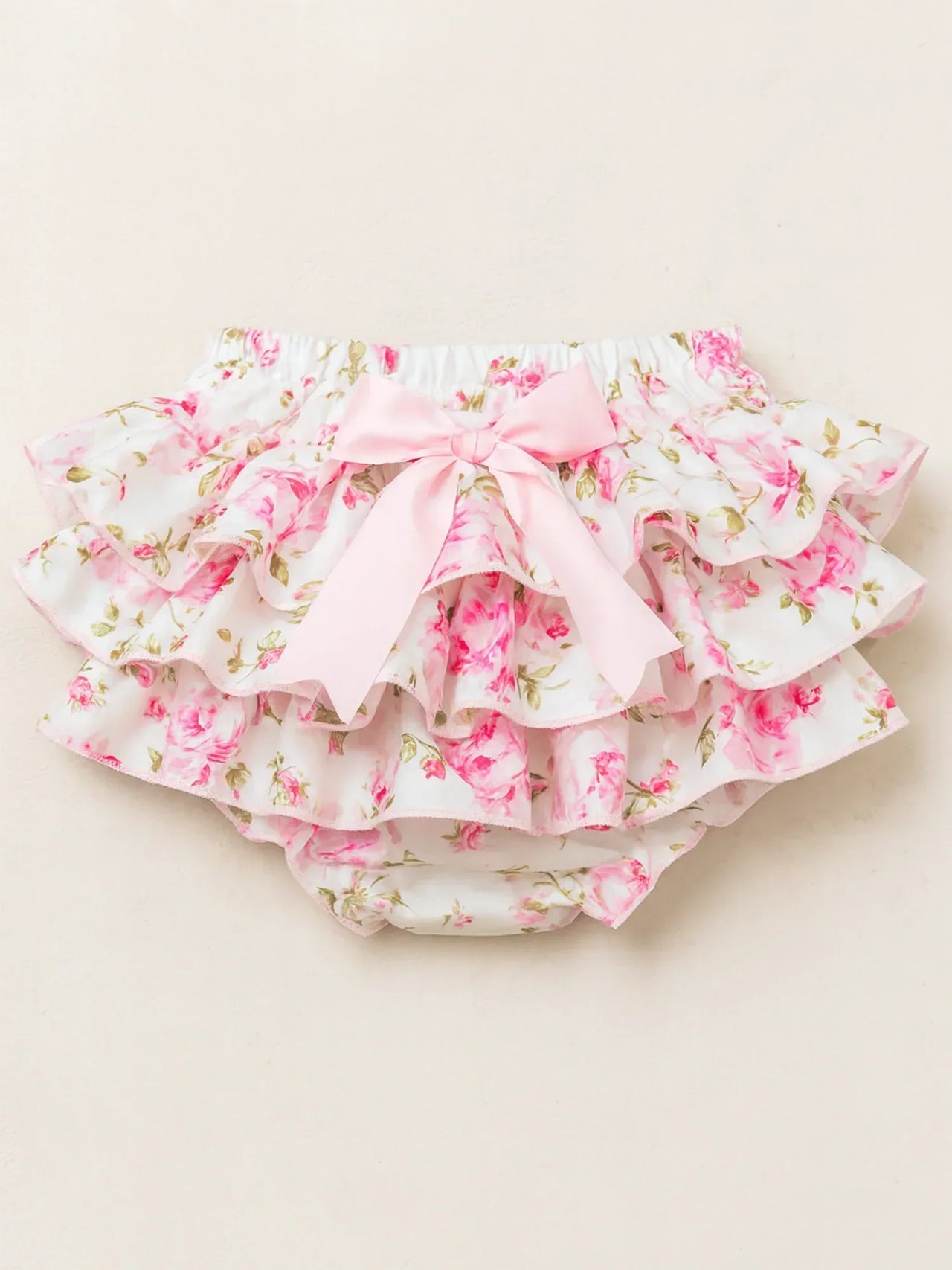 Floral baby bloomers with ruffles on a beige background