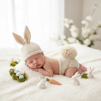 Thumbnail for Newborn baby in a bunny outfit surrounded by Easter decorations on a soft surface.