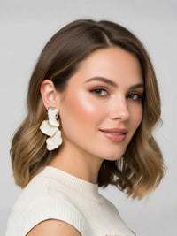 Thumbnail for Woman wearing gold floral earrings against a plain background