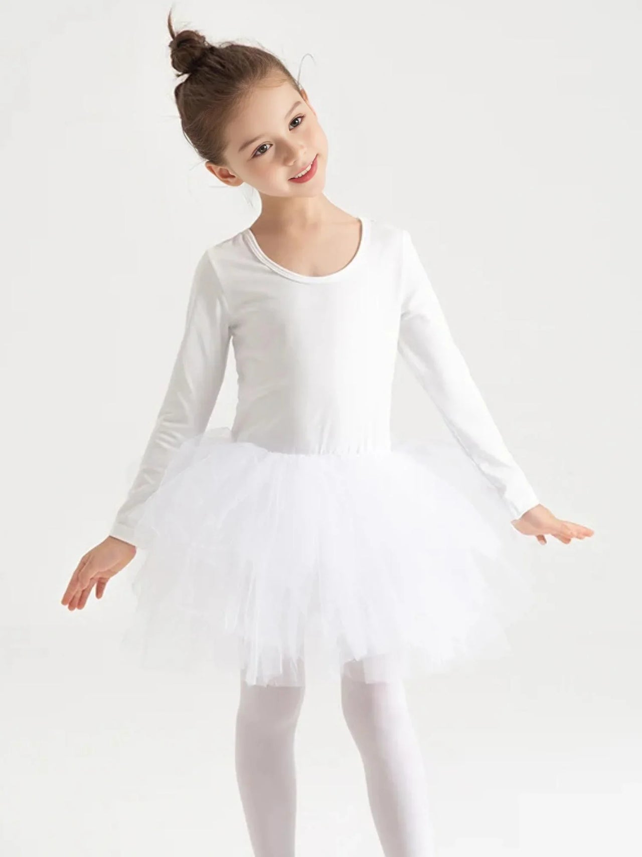 Young girl in a white long sleeved ballet tutu dress against a light gray background