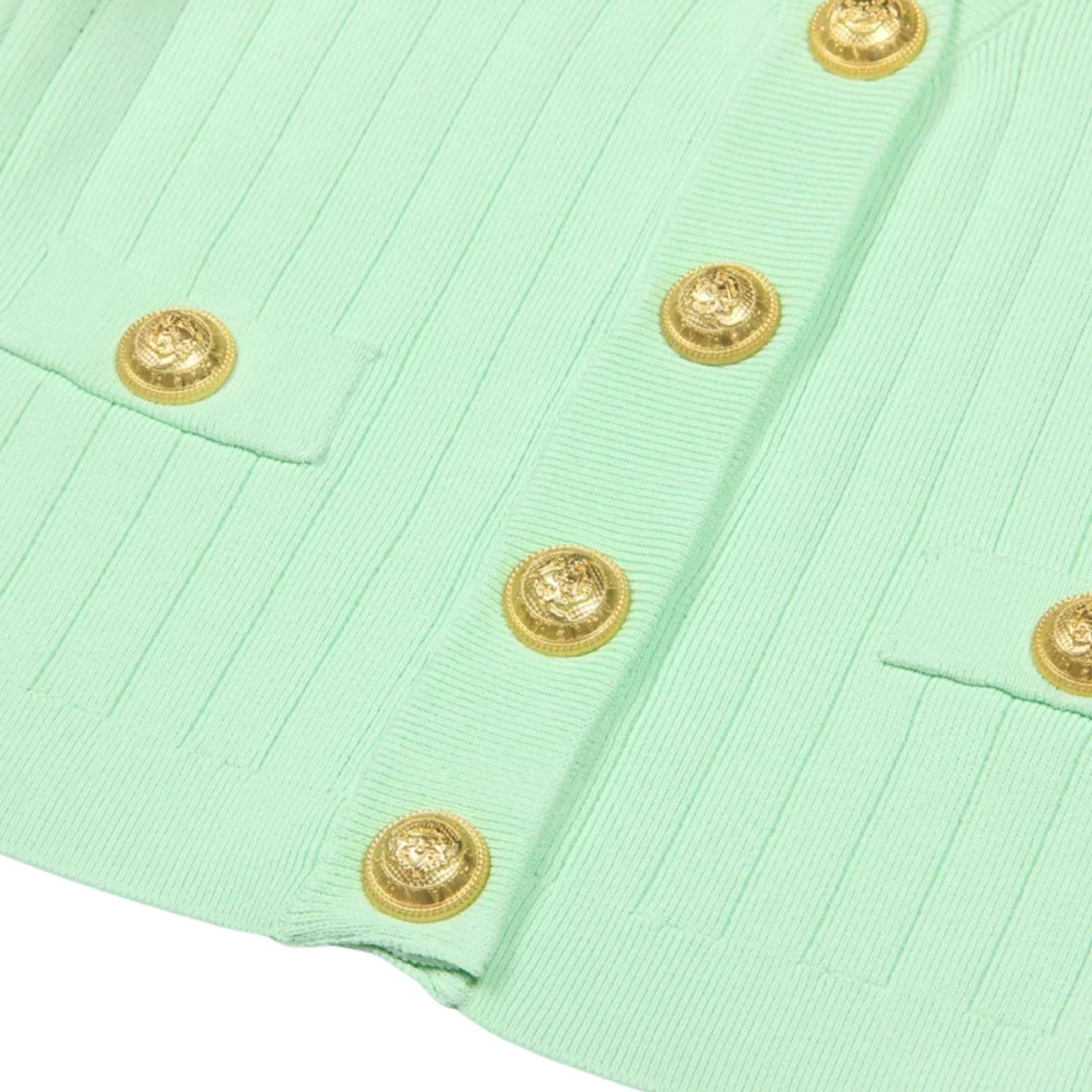 Close-up of a green fabric with gold buttons on a white background