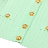 Thumbnail for Close-up of a green fabric with gold buttons on a white background