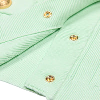 Thumbnail for Close-up of a light green fabric with gold buttons on a white background