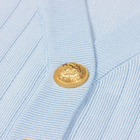 Thumbnail for Close-up of a light blue textured fabric with a gold button.
