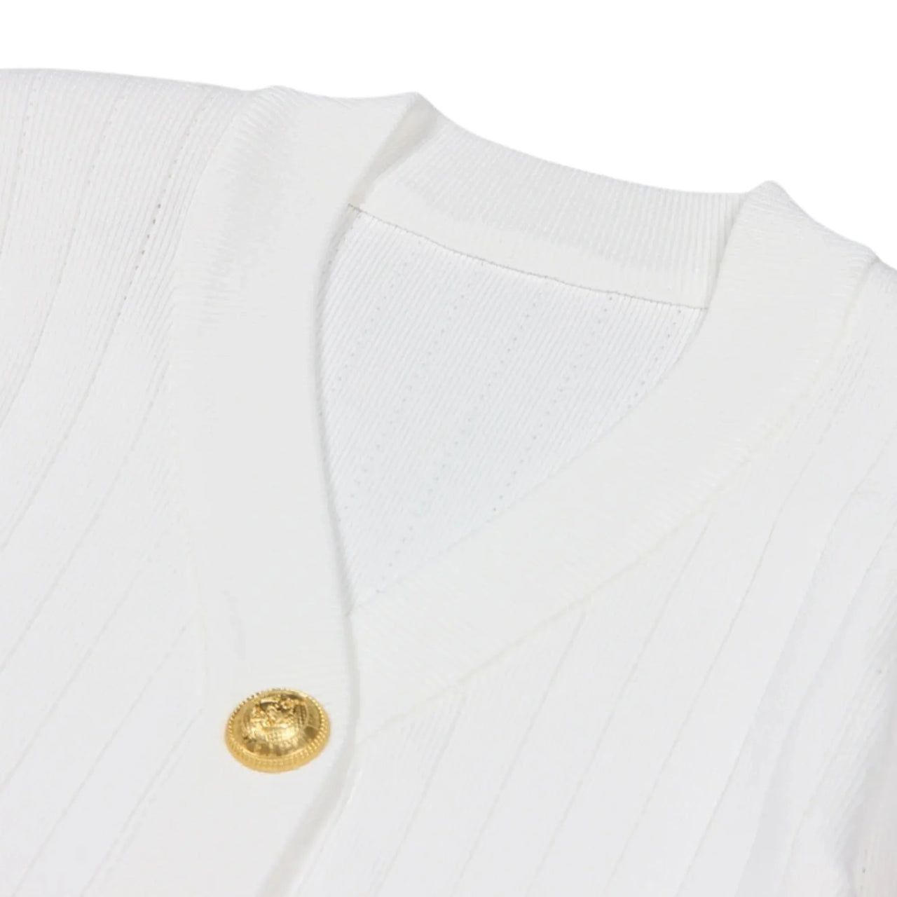 Close-up of a white garment with a gold button on a white background