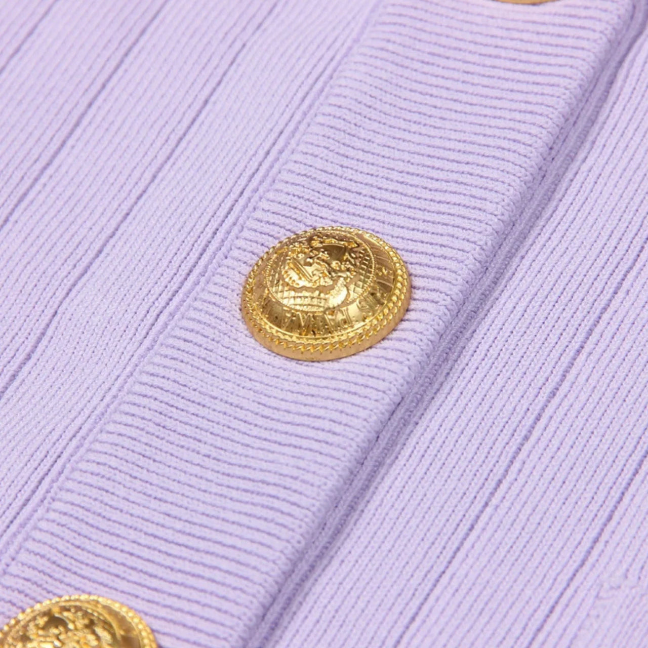 Close-up of a light purple cardigan with a gold button on a white background