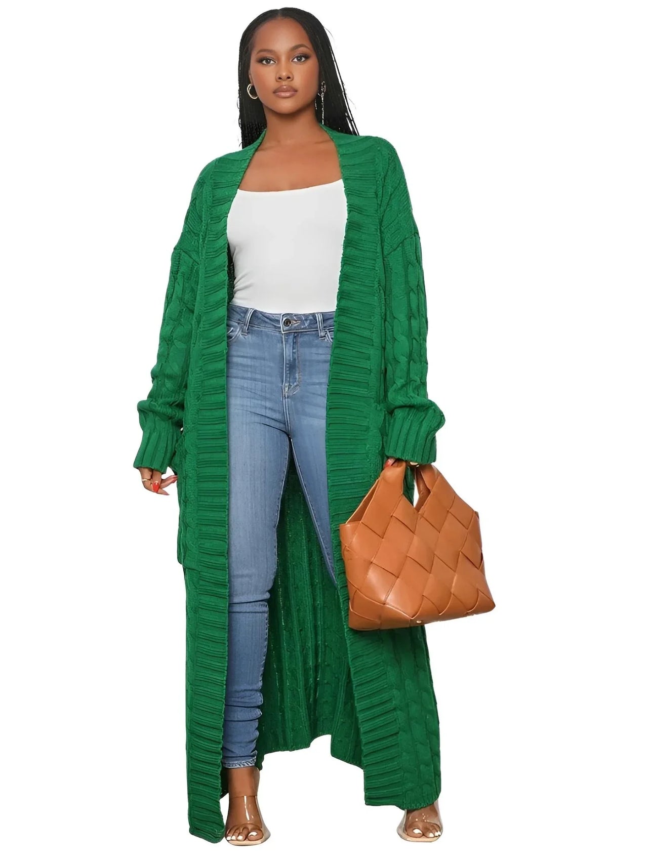 Woman wearing a long green cardigan, white top, blue jeans, and holding a brown bag on a white background