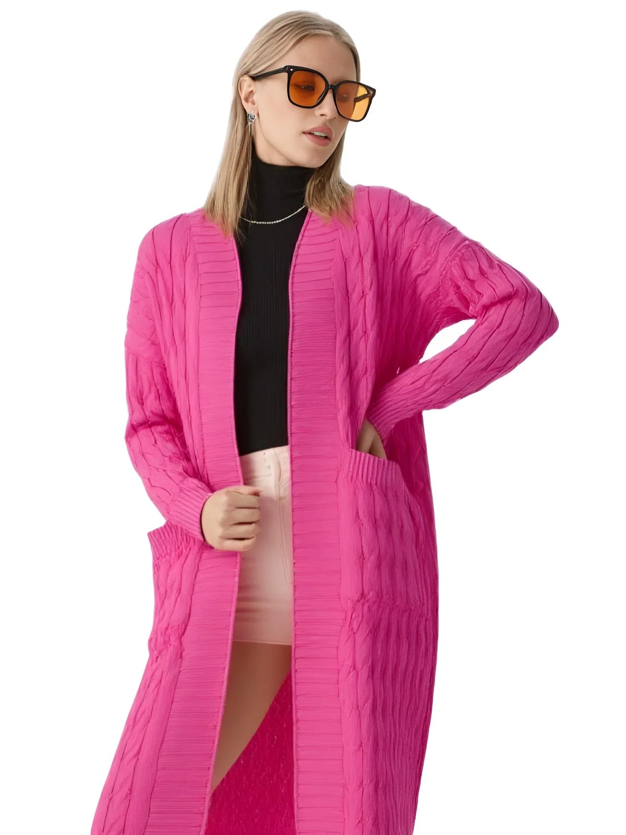 Person wearing a long pink cardigan over a black top and pink skirt on a white background