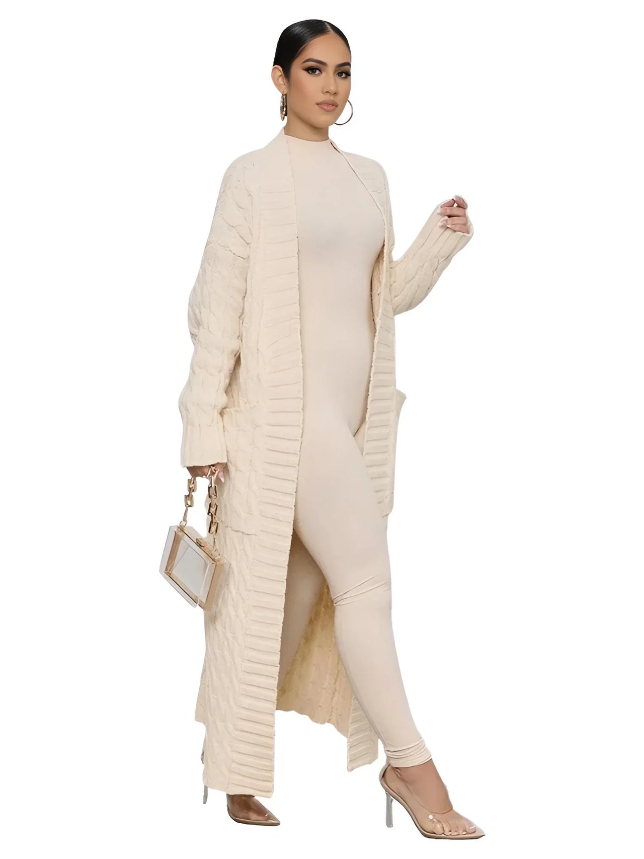 Woman wearing a long beige cardigan over a matching one piece jumpsuit on a white background