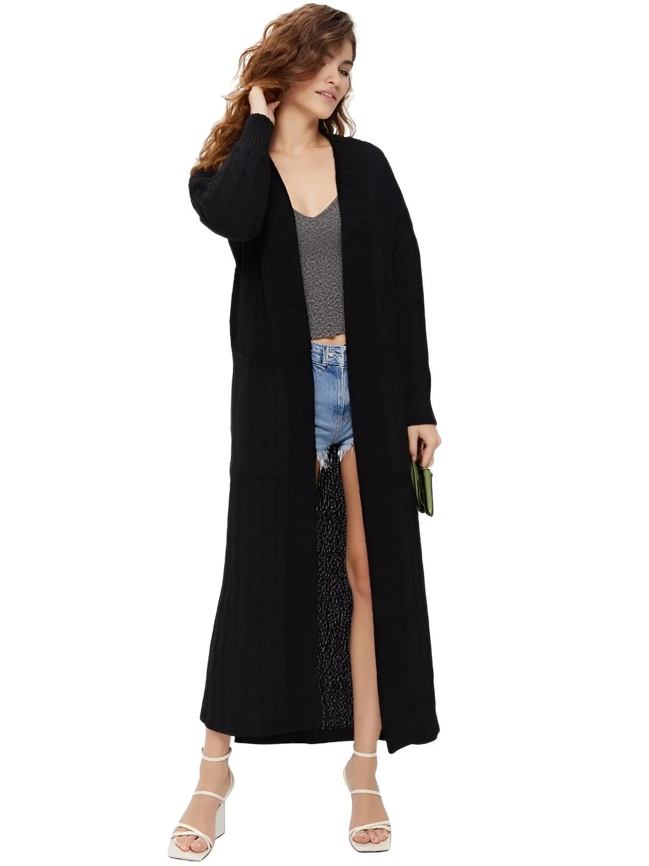 Woman wearing a long black cardigan over a casual outfit on a white background