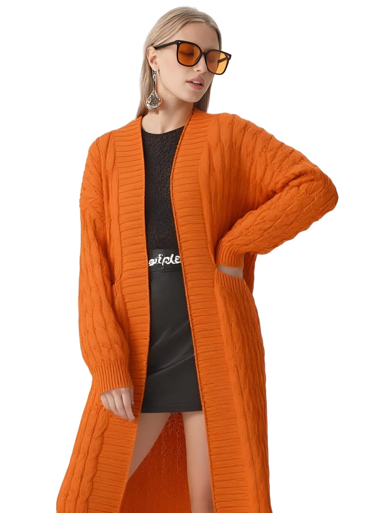 Woman wearing an orange cardigan over a black dress on a white background