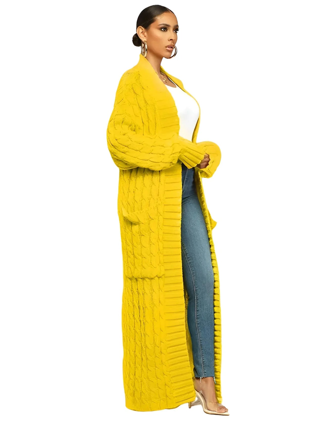 Woman wearing a long yellow cardigan over a white top and blue jeans on a white background