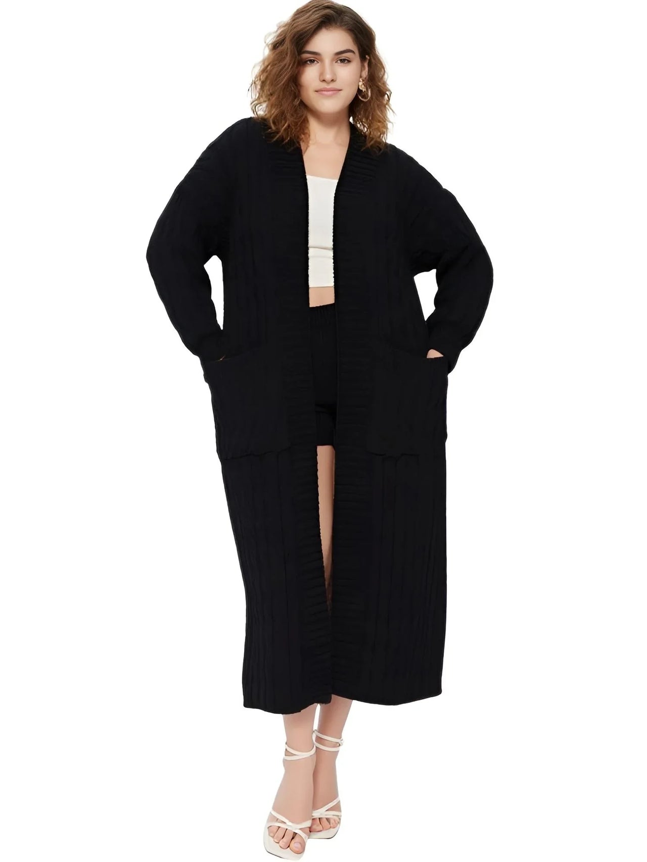 Woman wearing a long black cardigan over a white top on a white background