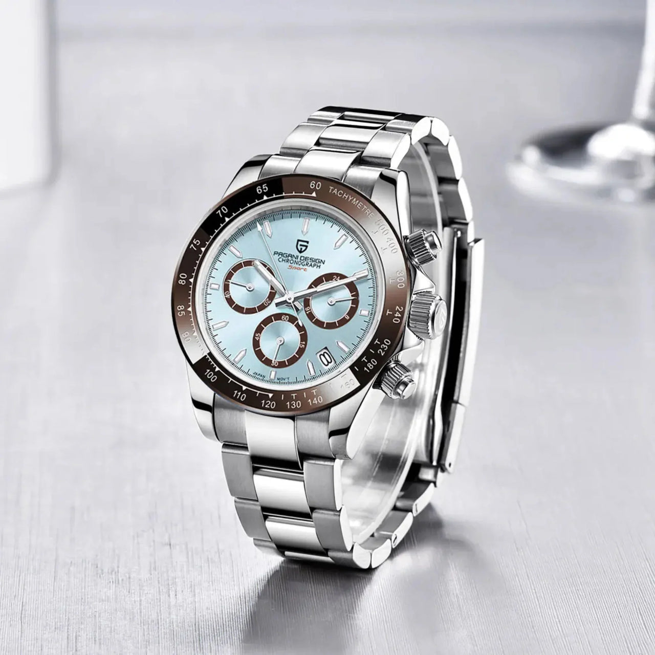 Silver watch with a light blue face on a reflective surface