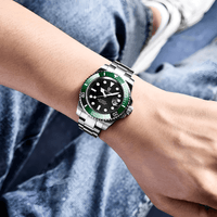 Thumbnail for Wrist wearing a watch with a green bezel and black face, against a denim background.