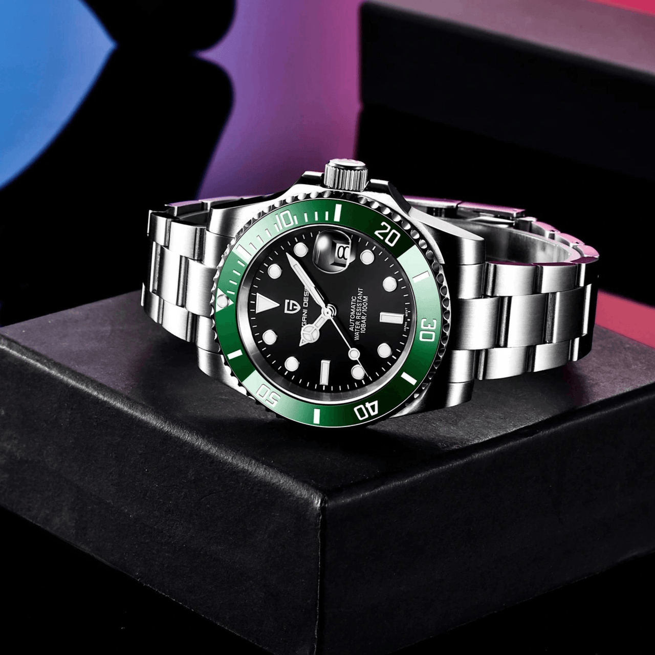 Luxury watch with green bezel and silver band on a black box