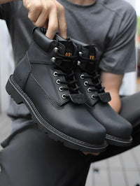 Thumbnail for Person holding a pair of black leather boots with visible brand name.