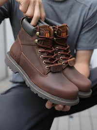 Thumbnail for Brown leather boots held by a person wearing a gray shirt.