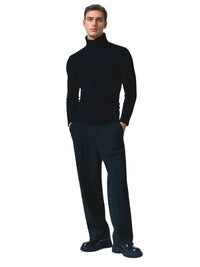 Thumbnail for Man wearing a black turtleneck sweater and dark pants on a white background