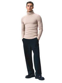 Thumbnail for Man wearing a beige turtleneck sweater and black pants on a white background