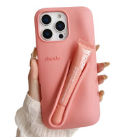 Thumbnail for Pink silicone lipstick iPhone case with a matching lip balm held by a hand on a white background