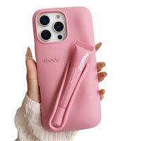 Thumbnail for Pink silicone lipstick iPhone case with a matching lip balm held by a hand on a white background