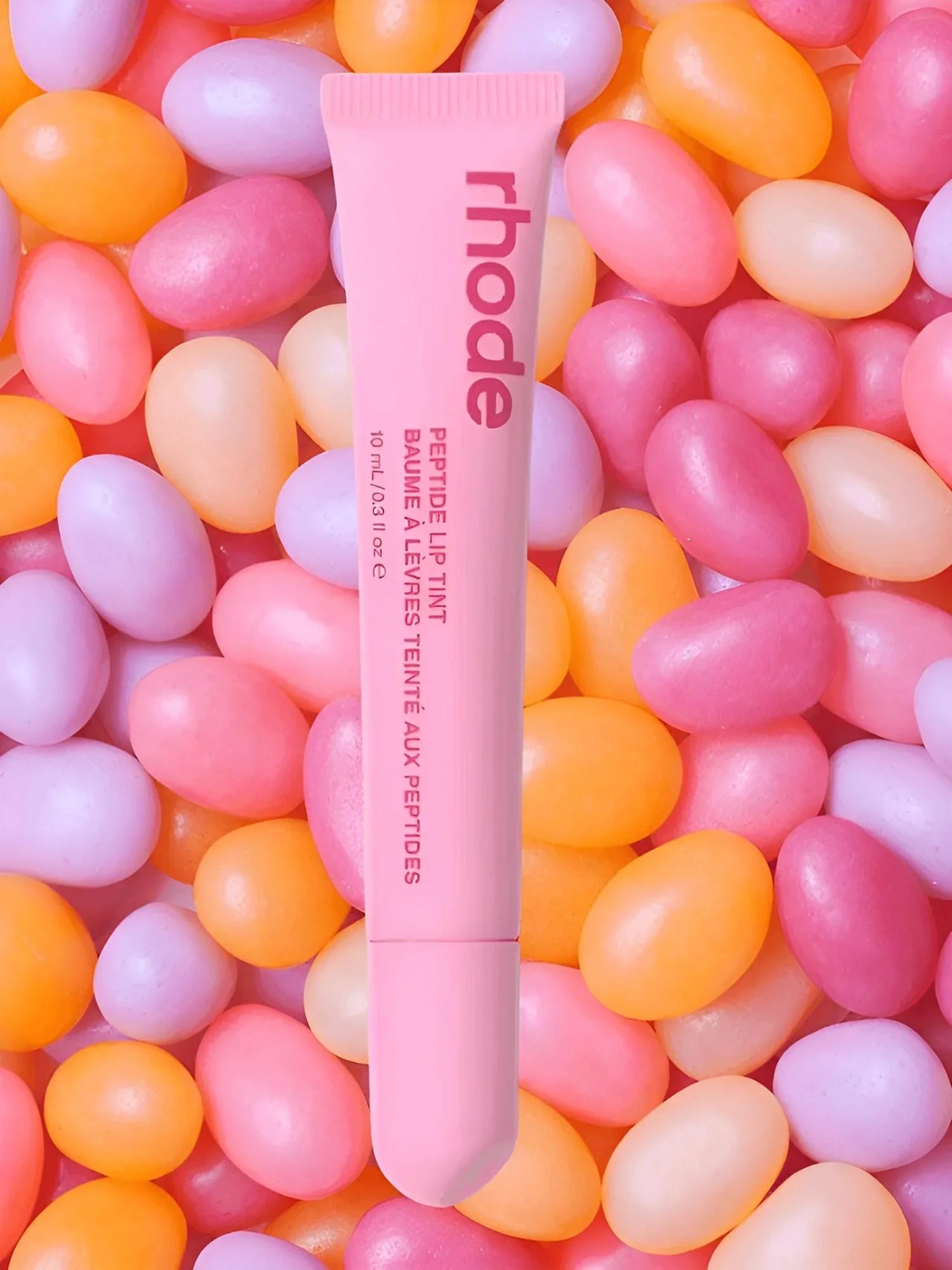 Jelly bean lip balm with 'rhode' branding on a colorful jelly bean background