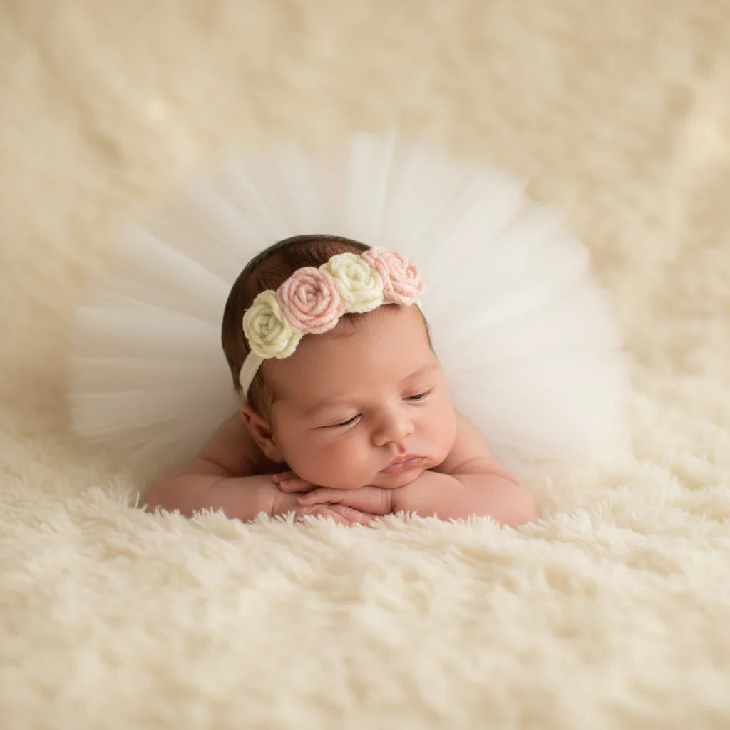 Newborn baby wearing a floral headband on a soft, beige background