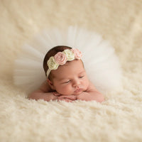 Thumbnail for Newborn baby wearing a floral headband on a soft, beige background