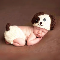 Thumbnail for Newborn baby wearing a crocheted dog hat and diaper on a brown background