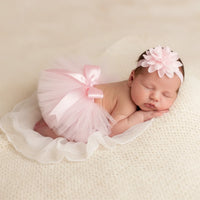 Thumbnail for Newborn baby in a pink tutu and headband on a beige blanket