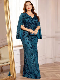 Thumbnail for Woman wearing a plus size teal evening gown with floral patterns in an elegant room.