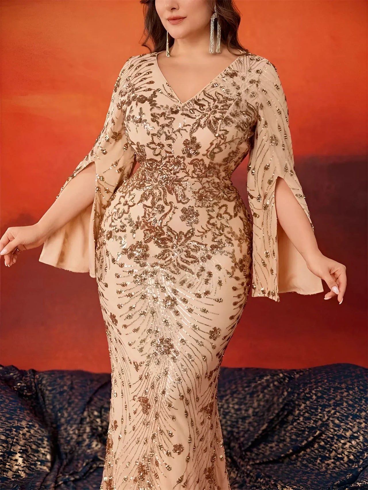 Woman in a plus size formal dress posing against an orange and red gradient background