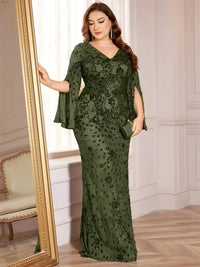Thumbnail for Plus size woman in an olive green evening gown standing next to a mirror in an elegant room.
