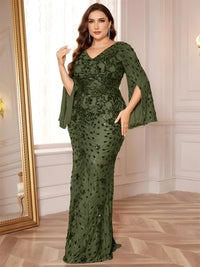 Thumbnail for Woman wearing an olive green evening gown with floral patterns in a room with wooden flooring and a mirror.
