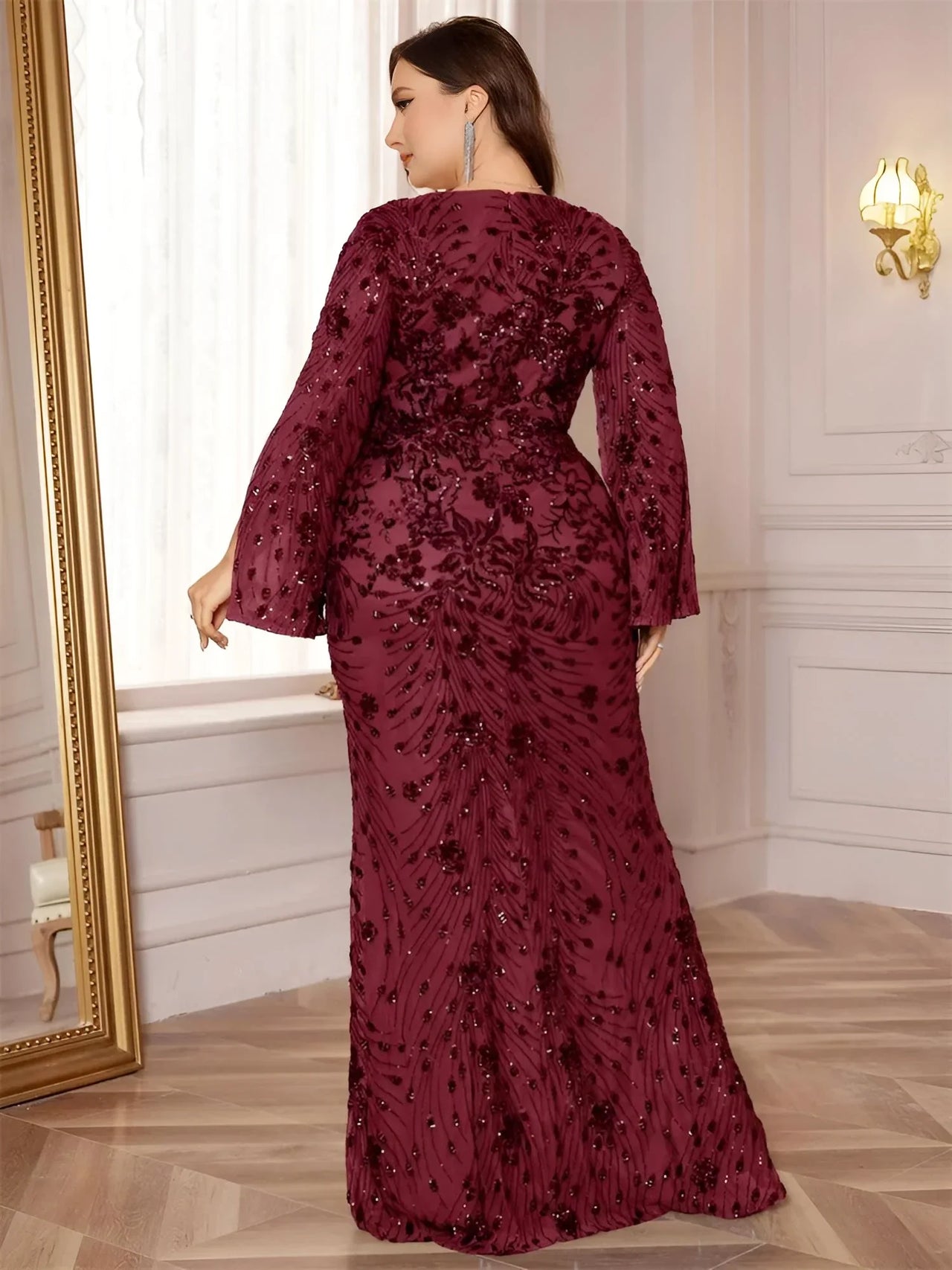 Plus size woman wearing a burgundy sequin dress in an elegant room.