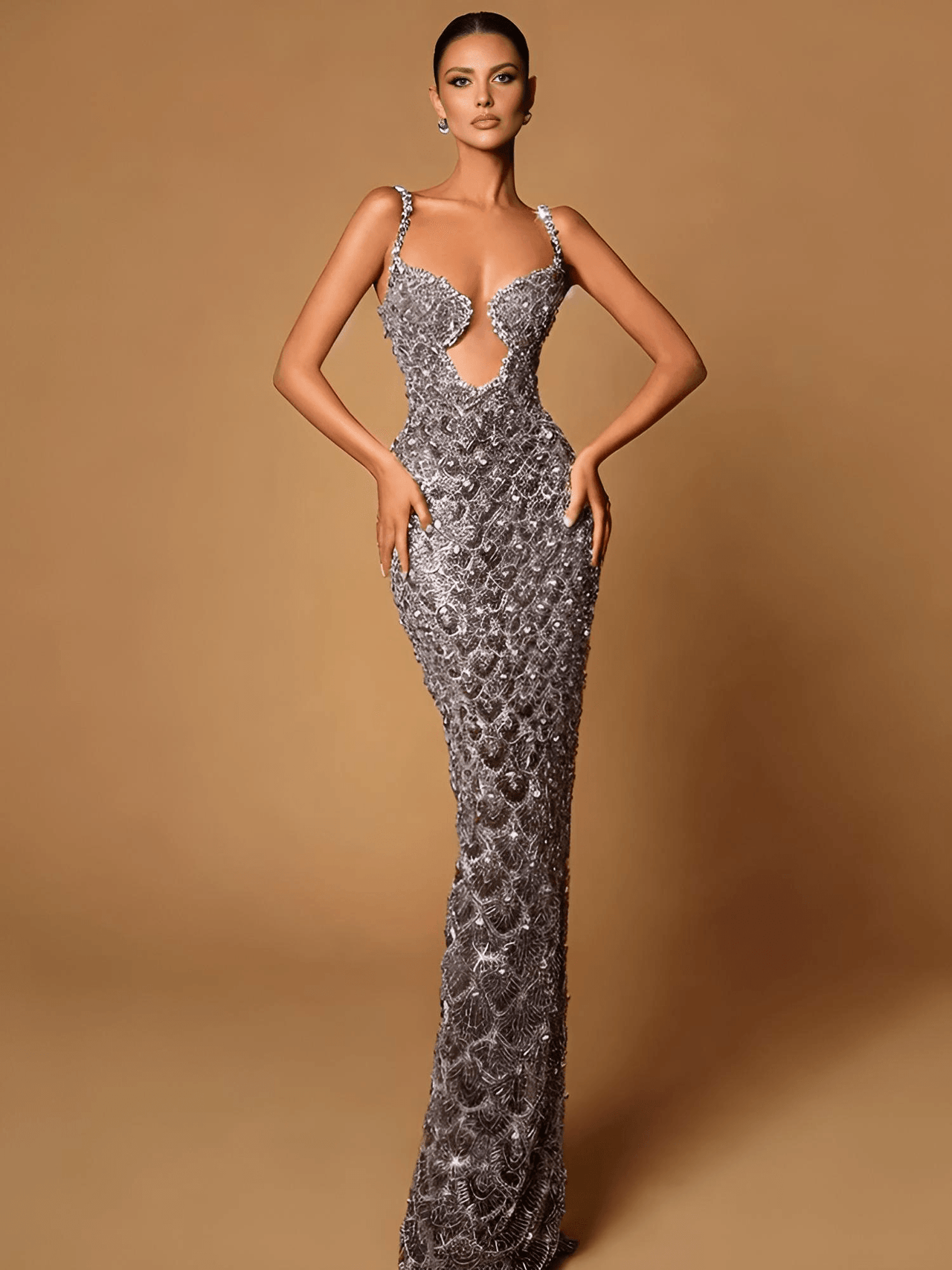 A woman in a sleeveless, deep-plunge, backless sequin dress with mesh paneling and an empire waistline.