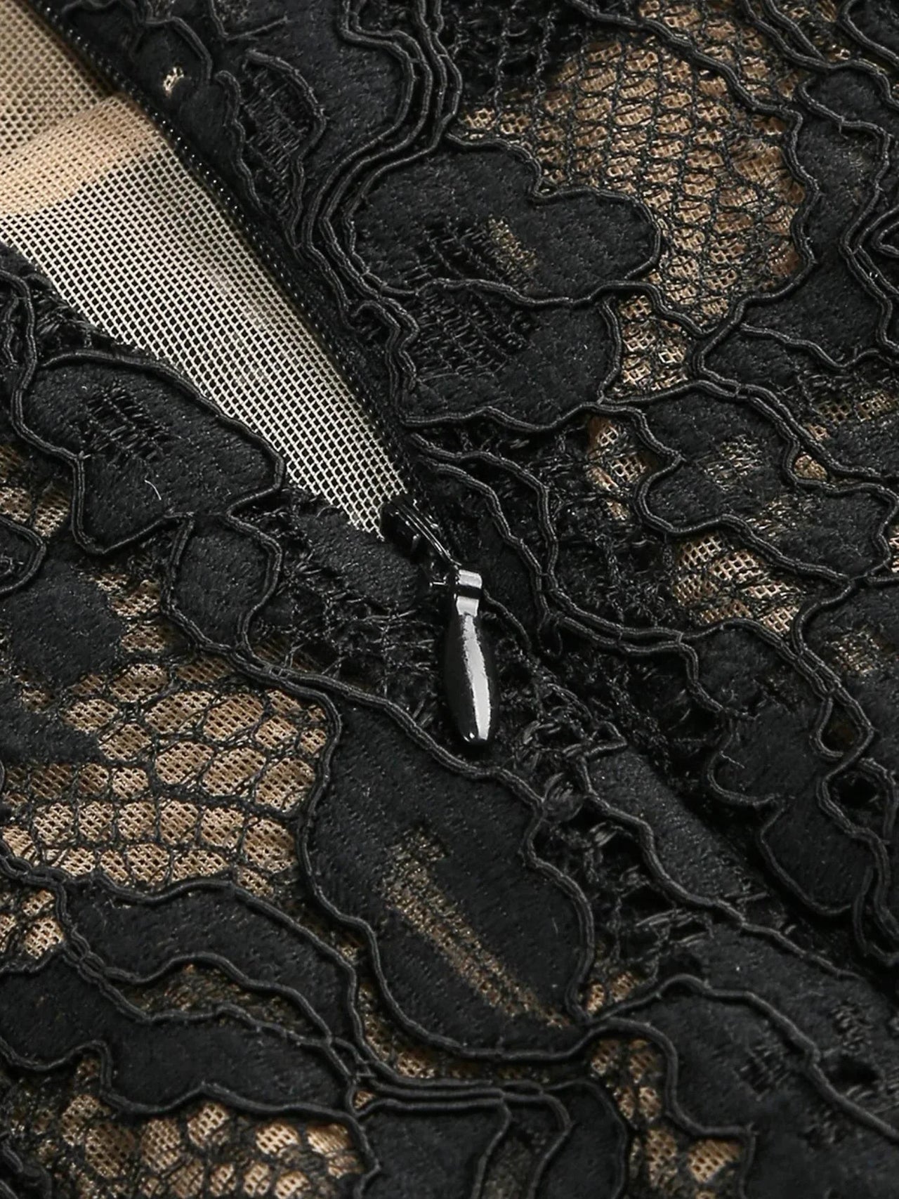 Close-up of black sheer lace dress fabric with a zipper and a nude liner