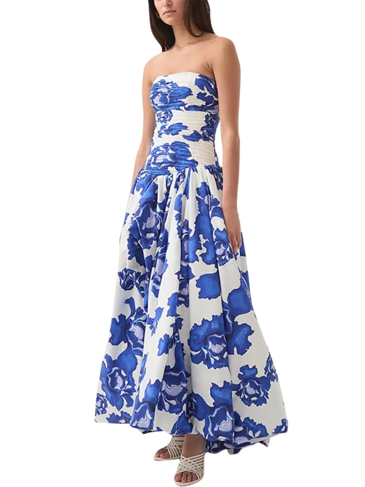 Woman wearing a blue floral strapless long bubble dress with a high slit on a white background